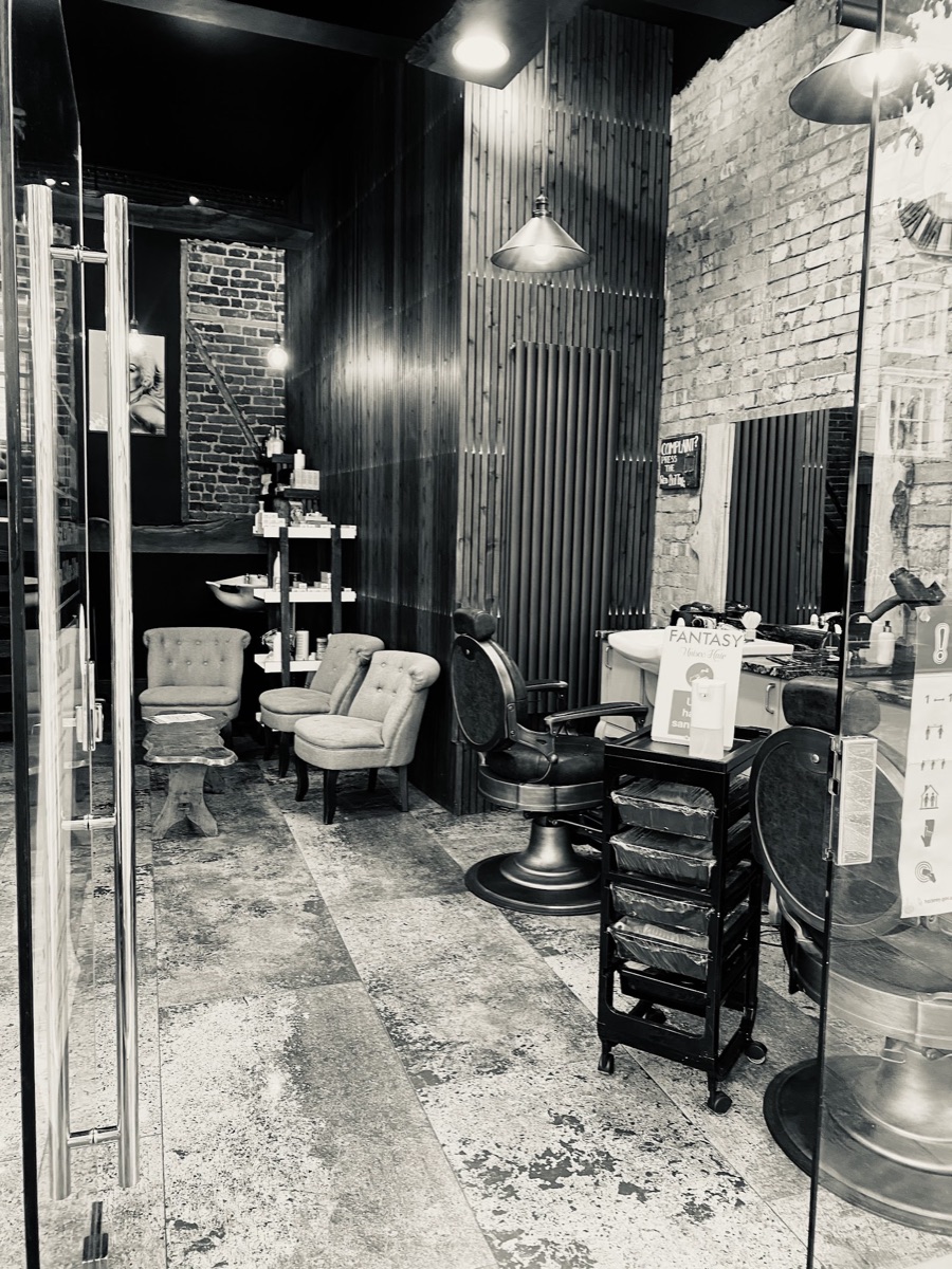 Inside Fantasy Hair Salon: exposed brick, wood-panelled walls, a vintage barber chair and warm brass pendant lighting